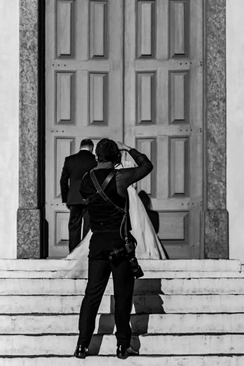 Fotograf mit zwei Kameras fotografiert das Brautpaar vor dem Portal einer Kirche