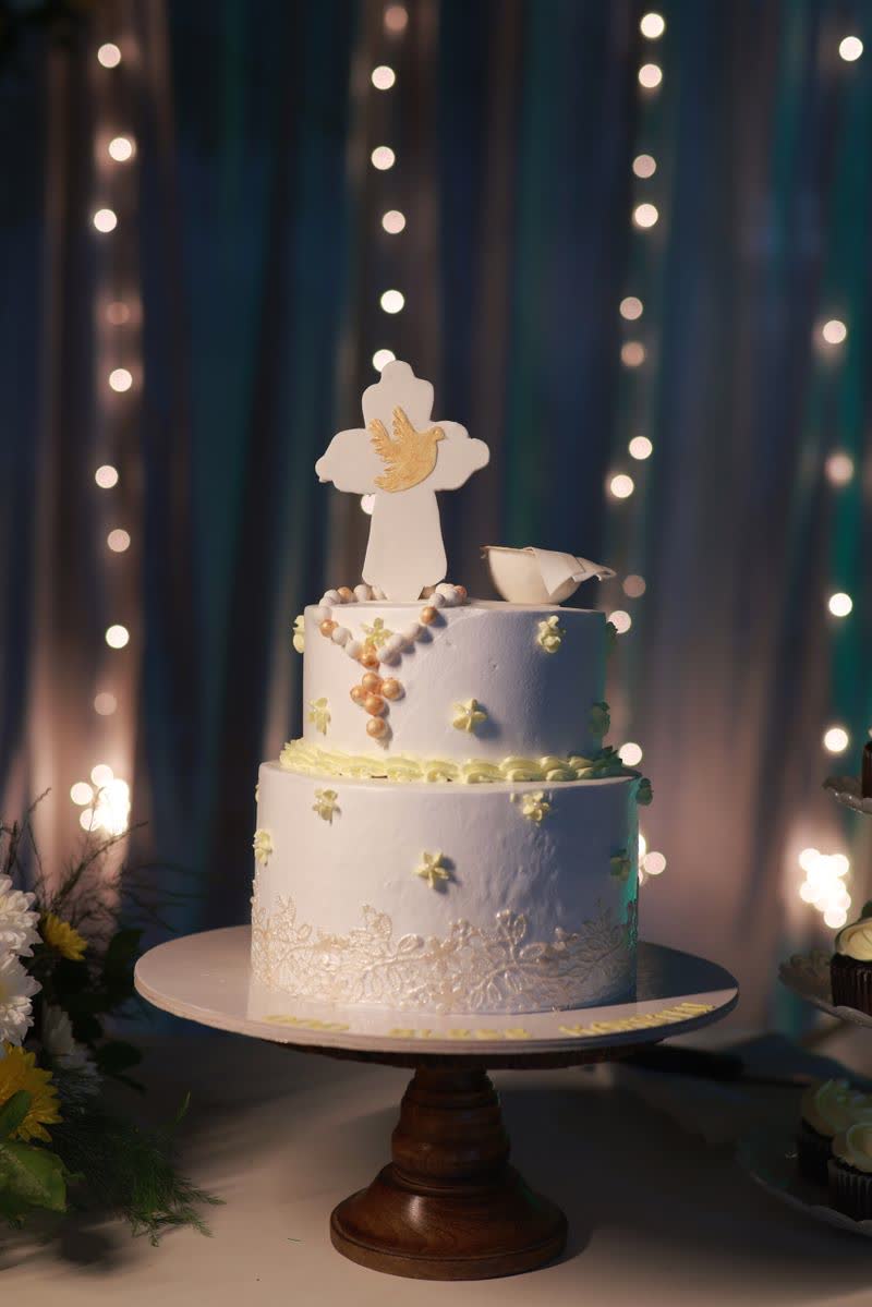 Zweistöckige Tauftorte mit Kreuz und Taube vor einer Lichterkette